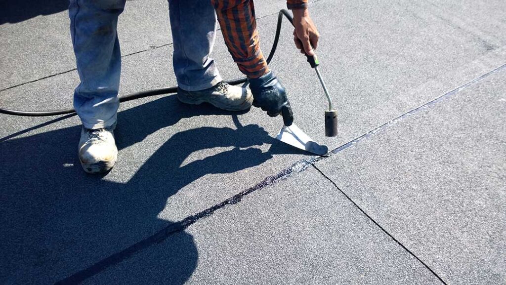 A homeowner reviews roof replacement documents beside a house with a clean, newly installed roof.
