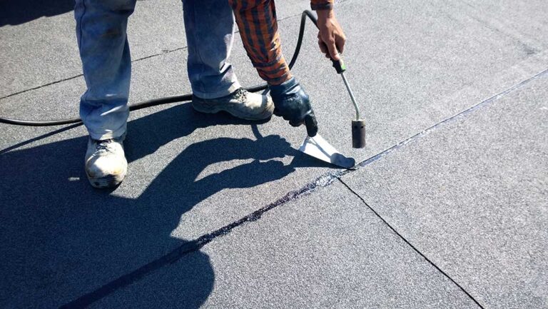 A homeowner reviews roof replacement documents beside a house with a clean, newly installed roof.